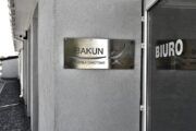 Wejście do biura Bakun Krzesła Obrotowe widoczne są drzwi z białą klamką i napisem biuro
