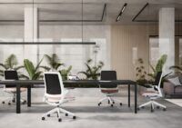 Biuro z betonową podłogą w którym stoją białe fotele biurowe smart z różowymi siedziskami przy czarnym biurku scena 1